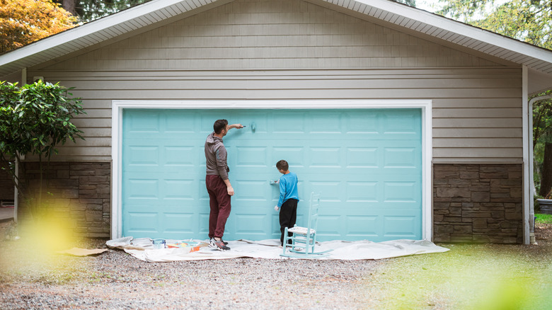 man paints garage door