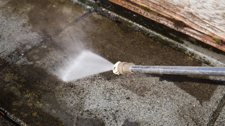 A close-up of someone power washing concrete tiles