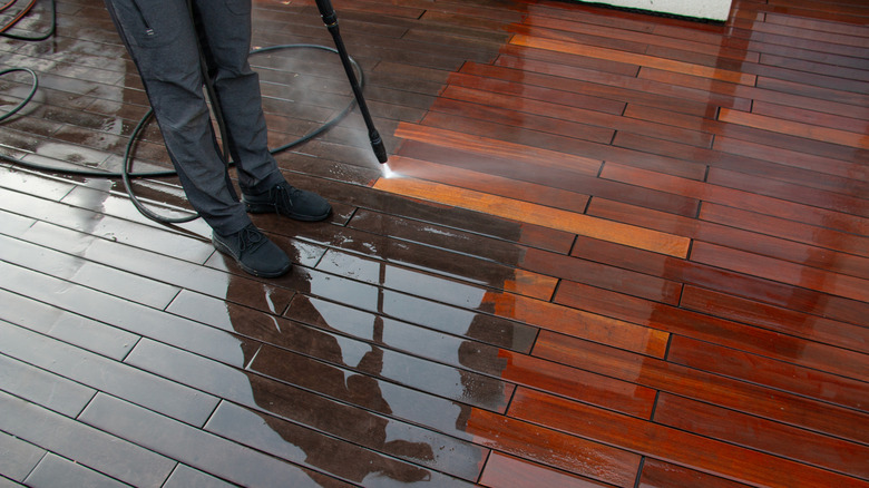 Someone cleaning a deck with a power washer