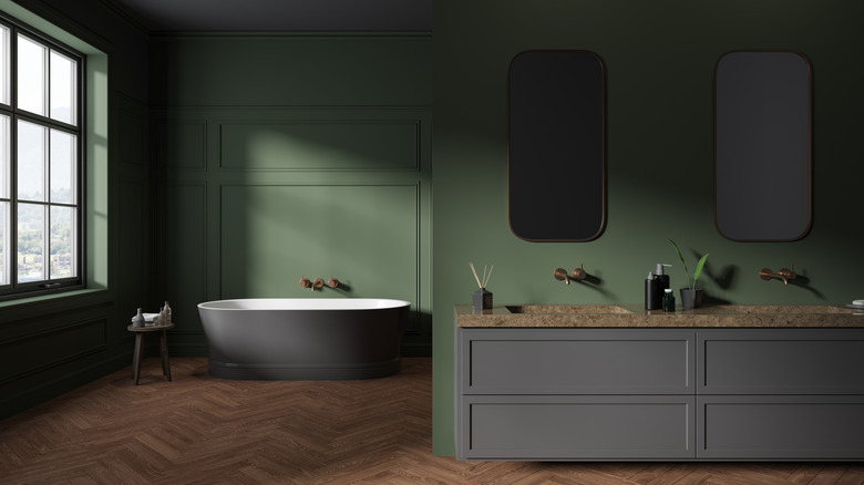 An indoor bathroom with a pair of mirrors over the sink is shaded dark, even with a large window