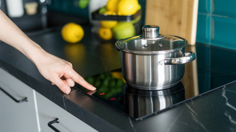 Hand using touchscreen on induction cooktop