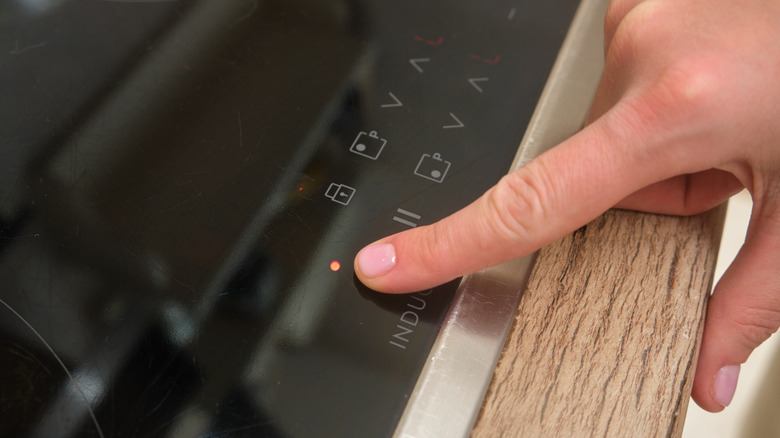 Close-up of finger next to lock icon on induction cooktop