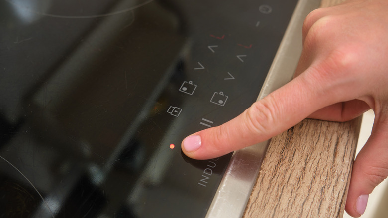 Finger pressing buttons on induction cooktop