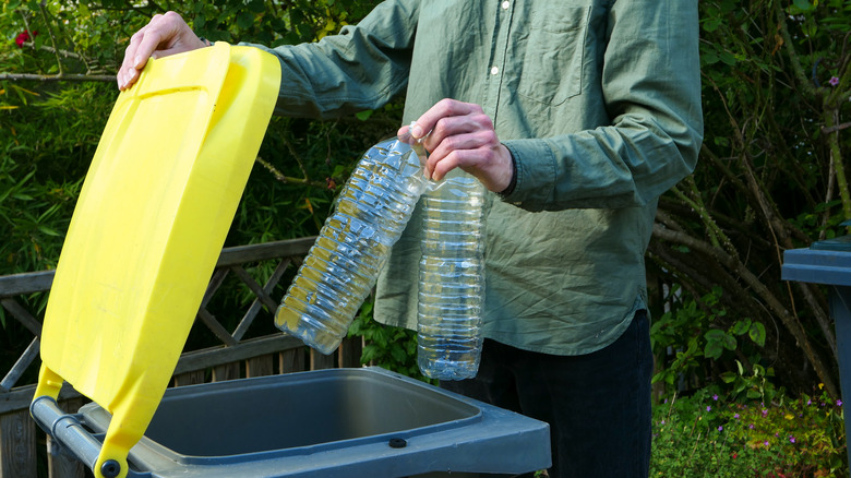 person throwing plastic bottles away