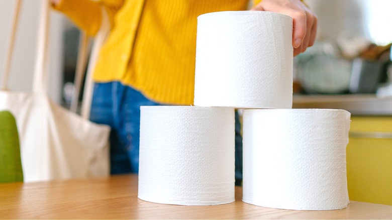 Person stacking toilet paper rolls