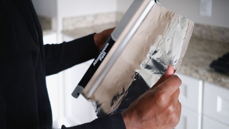 man holding roll of aluminum foil