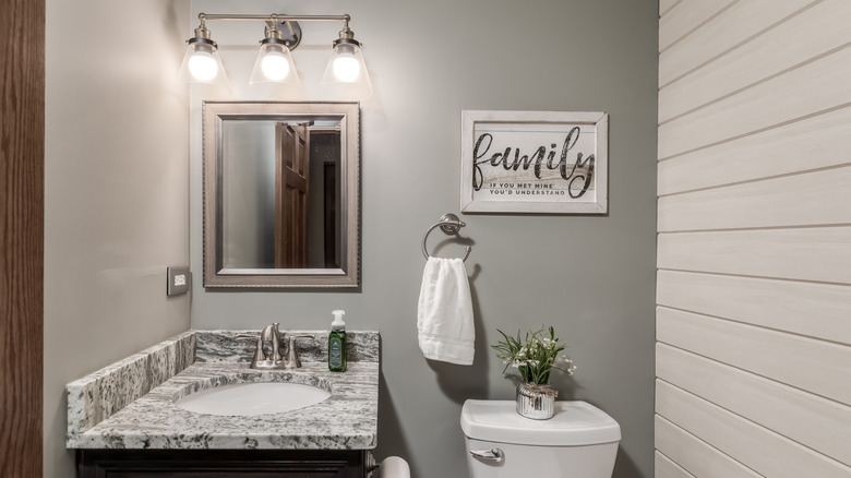 A dated greige bathroom features a shiplap covered accent wall