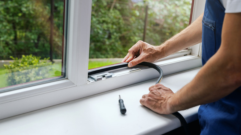 Man installing sealer tape on window