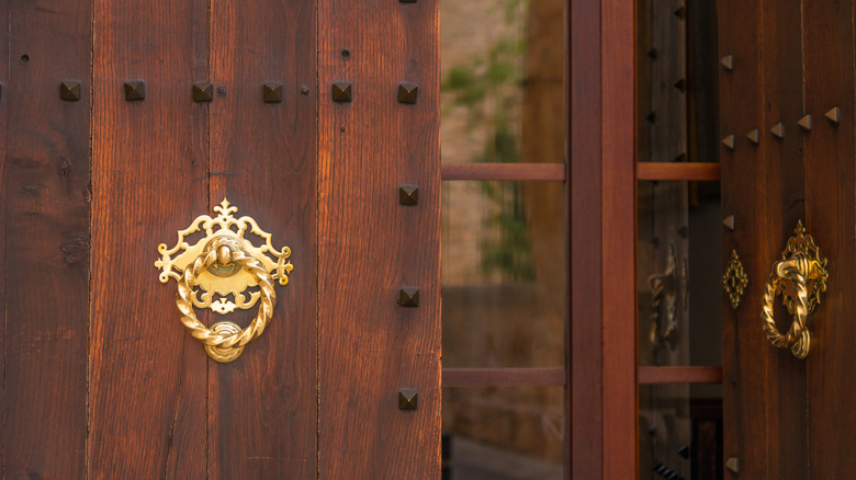 Double wooden doors with gold knockers and a keyhole charm