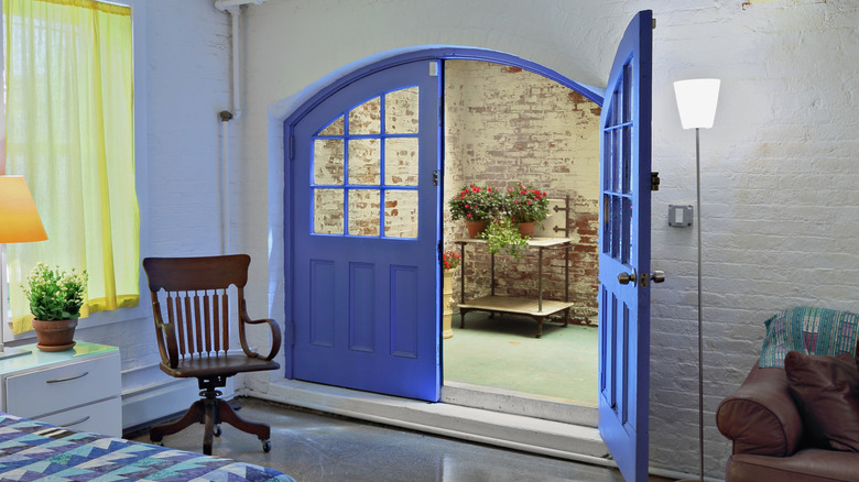 Stylish bedroom with half open french doors painted in a striking blue color