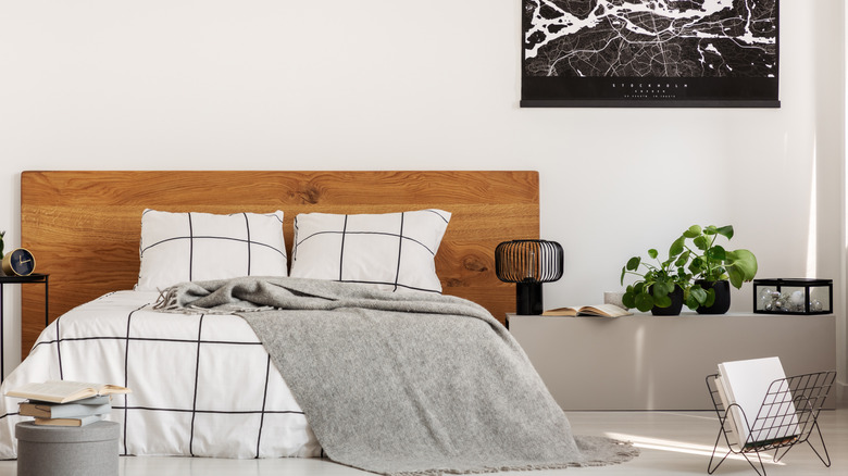 White wall with black map in modern bedroom with king size bed with wooden headboard.