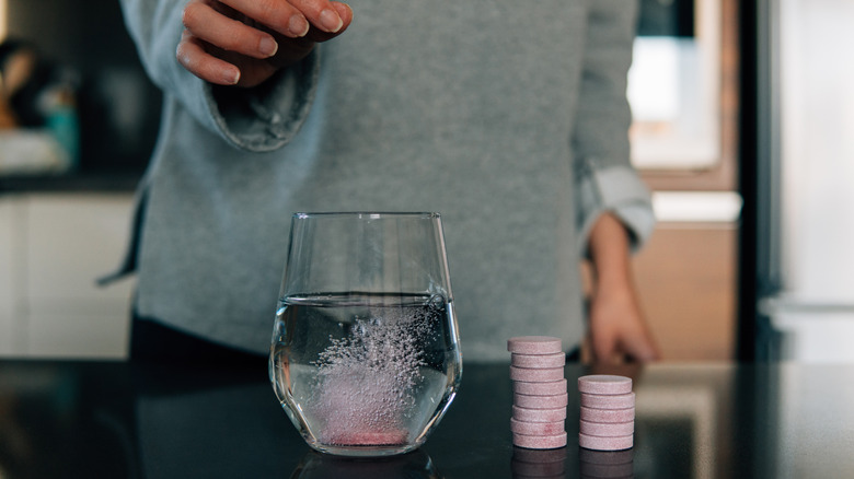 hand dropping an effervescent pink tablet into water