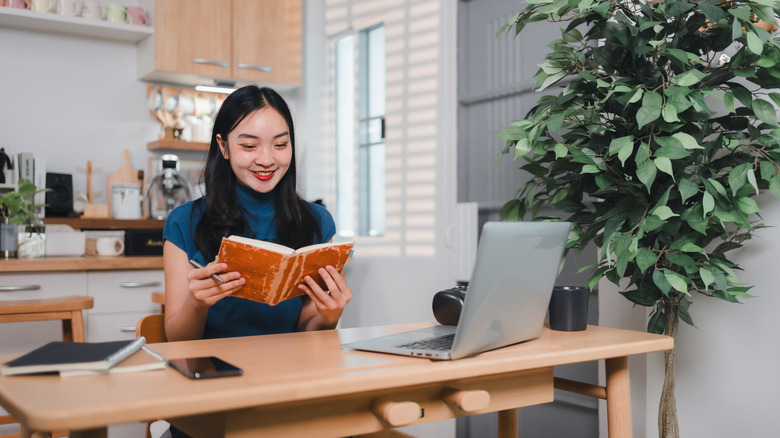 A smiling woman works at a desk in a kitchen