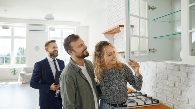 Home buyers looking at kitchen cabinets with the realtor looking on