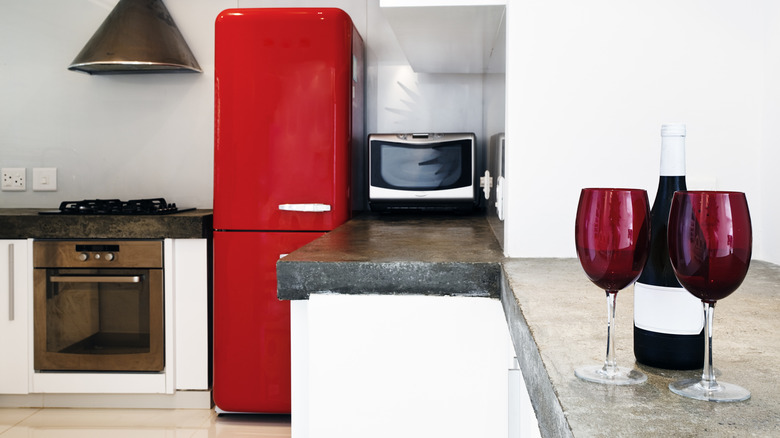 A dated kitchen with a red fridge