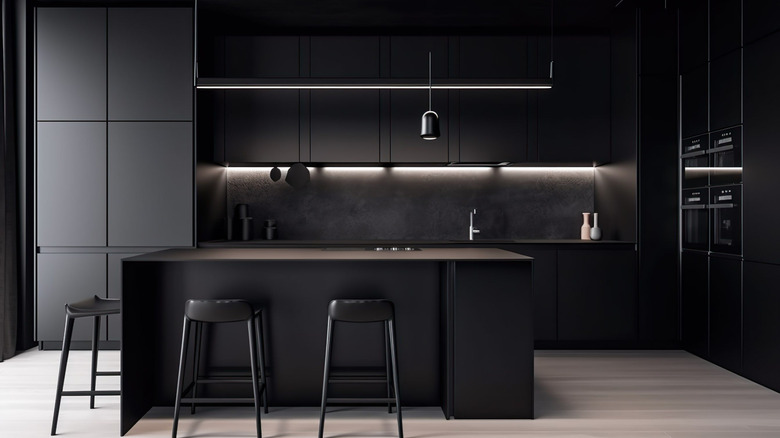 A black kitchen with built-in appliances and island with stools