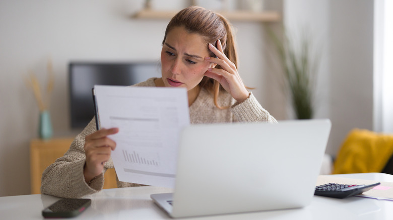 A person looking at an expensive bill with a worried frown