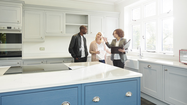 agent showing couple home's kitchen