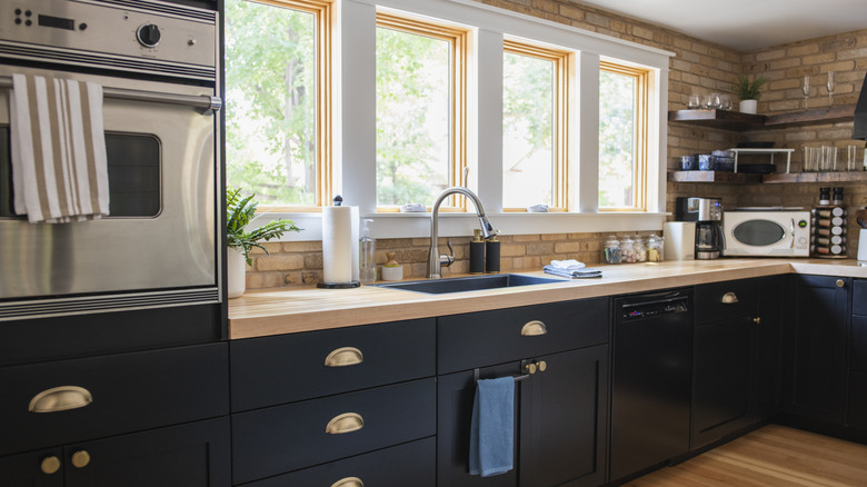 large modern styled kitchen with navy cabinets and brick accent wall