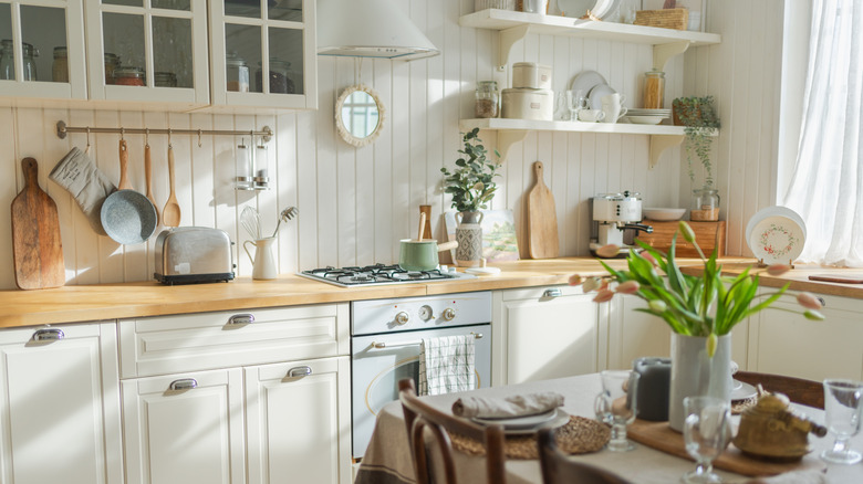 small white kitchen with lots of dishware and a couple open shelves on wall