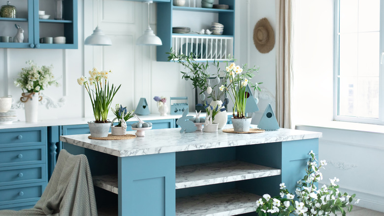A cozy kitchen with blue cabinets and white marble benchtops