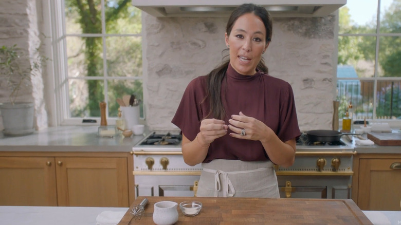 white oak cabinets with white stone walls and Joanna Gaines standing at the island