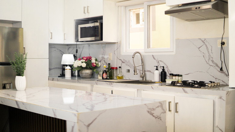 Kitchen in new luxury home with quartz waterfall island, hardwood floors, dark wood cabinets, and stainless steel appliances.