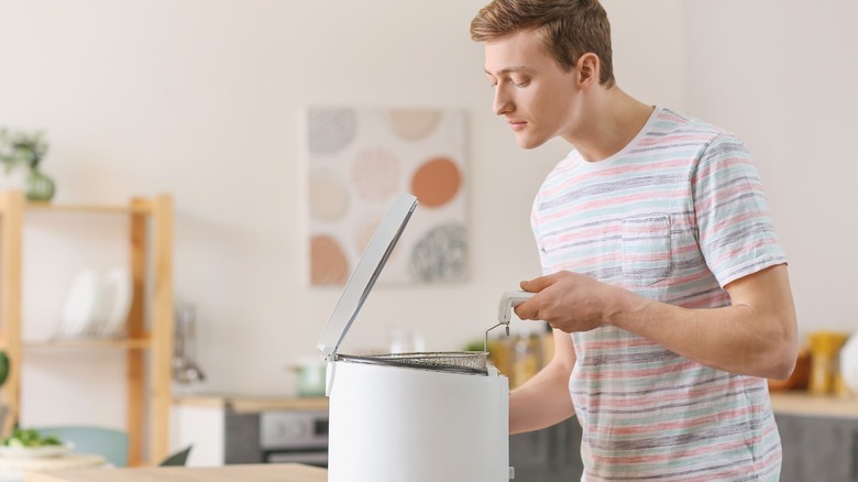 Man looking in basket of countertop fryer in kitchen