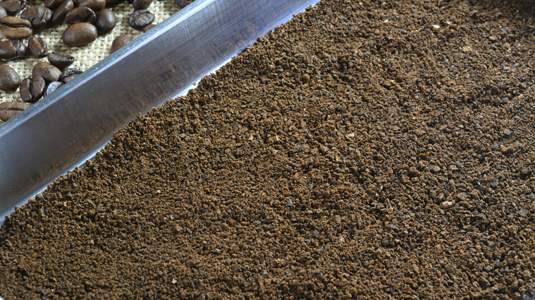 Fresh coffee grounds are being spread on a baking tray, one way of helping neutralize odors in places like your fridge.