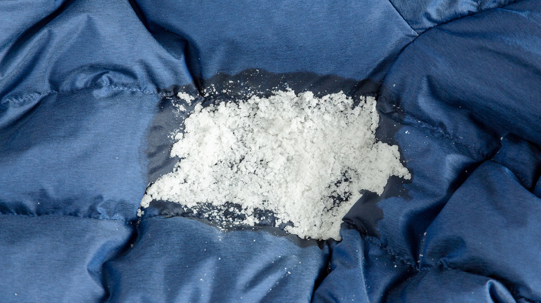 A large pile of salt sitting on a stained comforter.