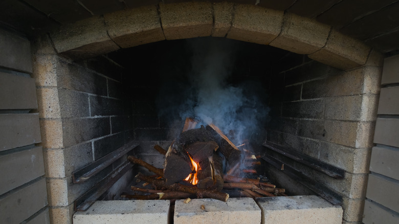 A fireplace showing burning logs and soot on bricks