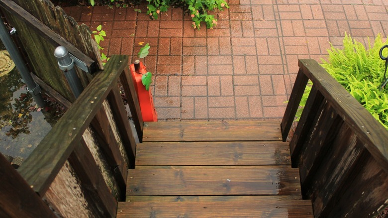 Wet wooden deck with rainwater and small twigs.