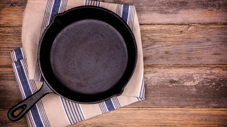 An empty cast iron pan on a stripped dish cloth