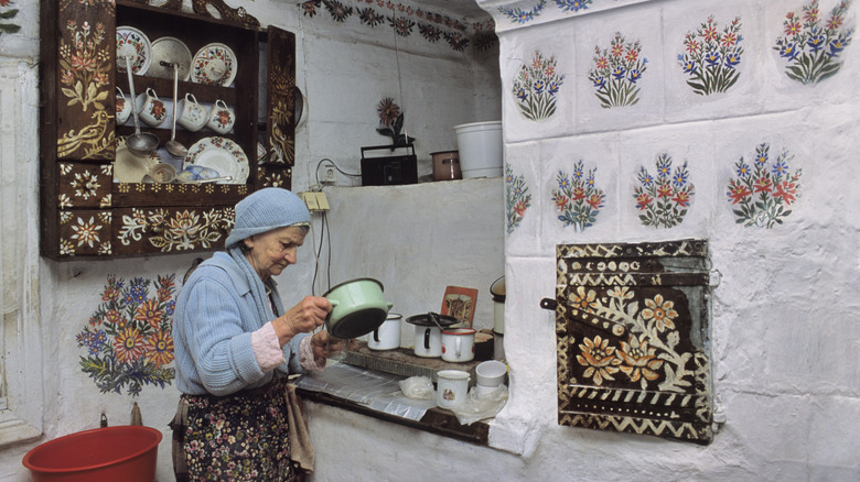 An old woman is looking at a pot in her hand