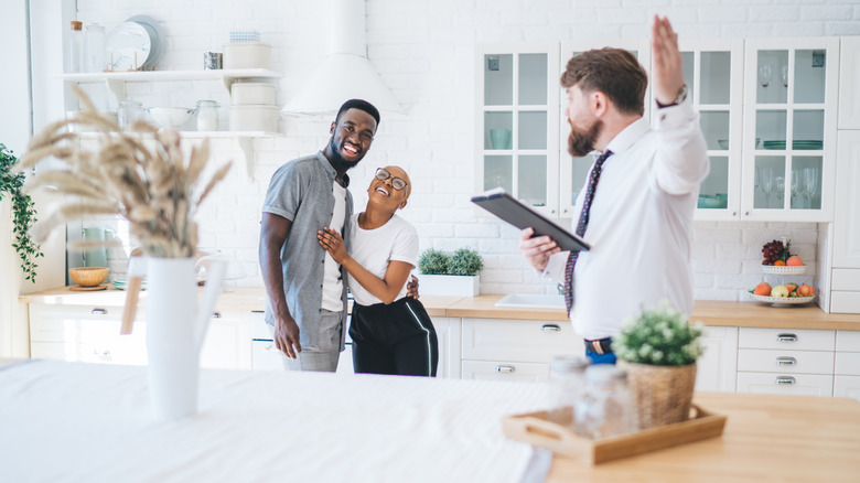Couple visiting home for sale with realtor, standing in kitchen