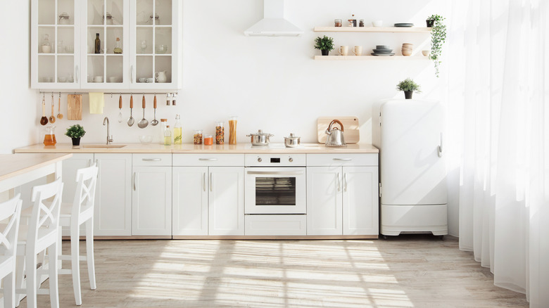 a modern kitchen with light colored flooring and white cabinets