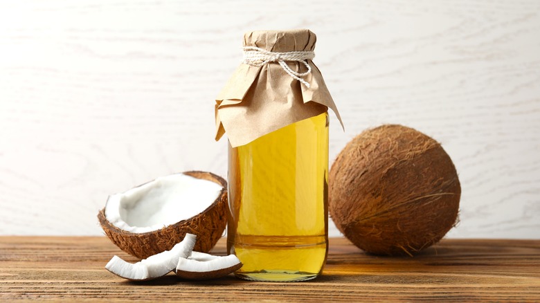 bottle of coconut oil next to coconuts