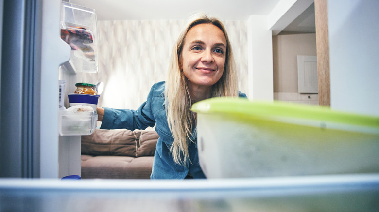 A person peeking into a refrigerator