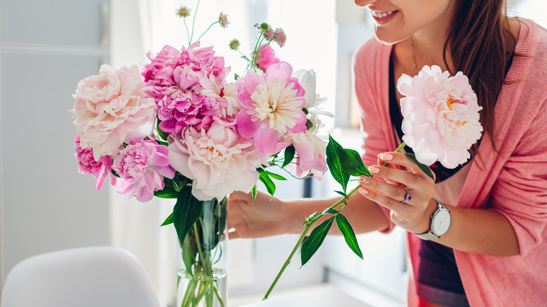 Woman arranging peonies in vase