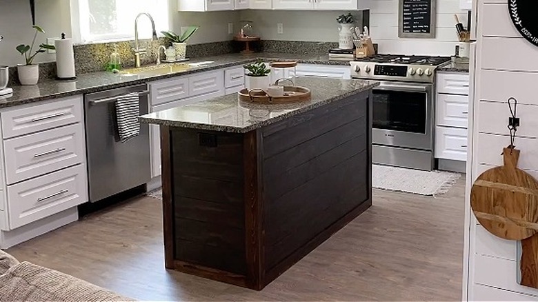 A stained shiplap kitchen island with white marble top in a contemporary rustic kitchen