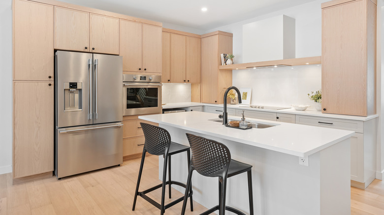 White kitchen island with a sink in a timber and white kitchen