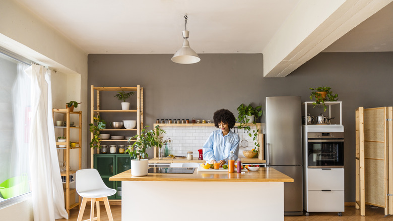 A woman cuts peppers at a kitchen island with a single pendant light hanging above