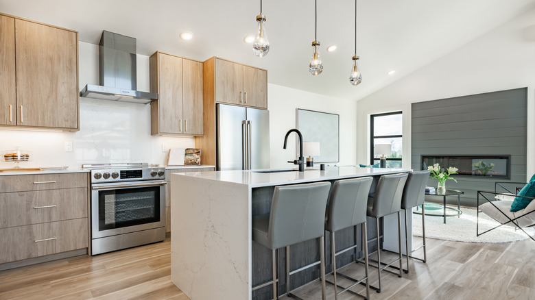 A well-lit kitchen features three hanging lights above the island
