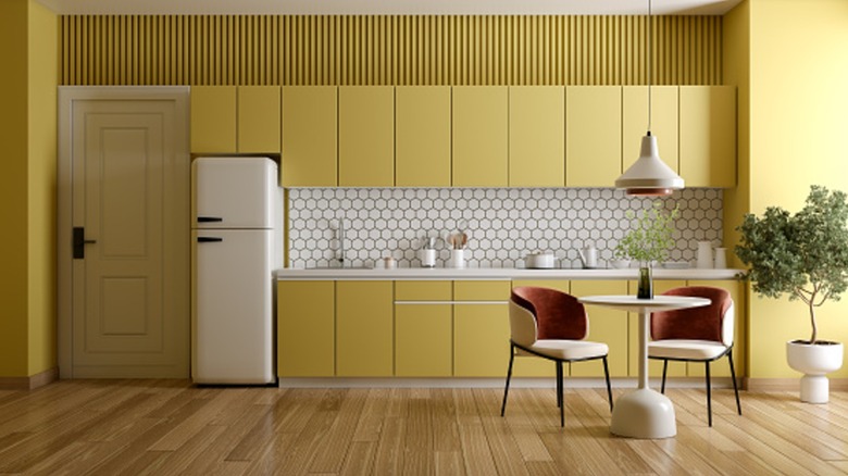 Yellow one-wall kitchen with a white retro fridge and a small dining table
