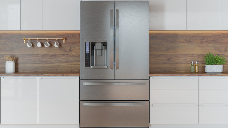 Stainless steel refrigerator next to white kitchen cabinets
