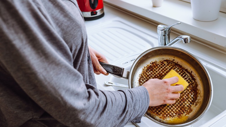 woman scrubbing burnt pan