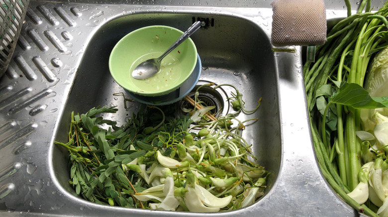 Double sink filled with green vegetable scraps