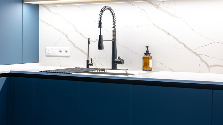kitchen with marble countertop, blue cabinets, and black sink