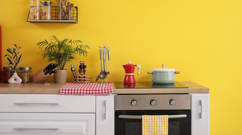 A yellow-walled kitchen displays essentials ready for people to use.