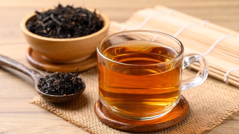 Black tea in a cup next to loose tea leaves